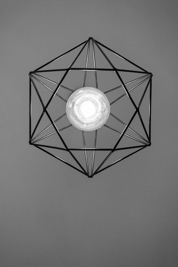 A minimalist black and white image of a geometric light bulb fixture, offering a modern and abstract aesthetic.